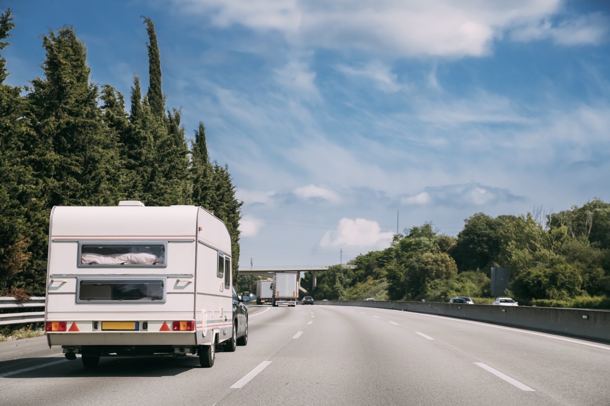Une voiture qui tire une roulotte sur l'autoroute.