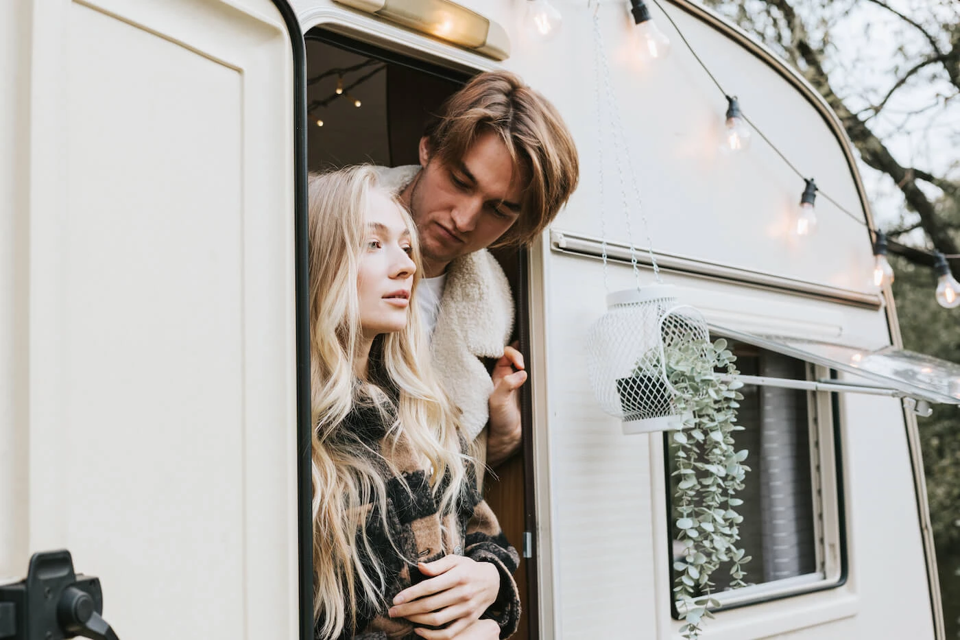 Un couple à la porte de leur petite roulotte à 2 personnes