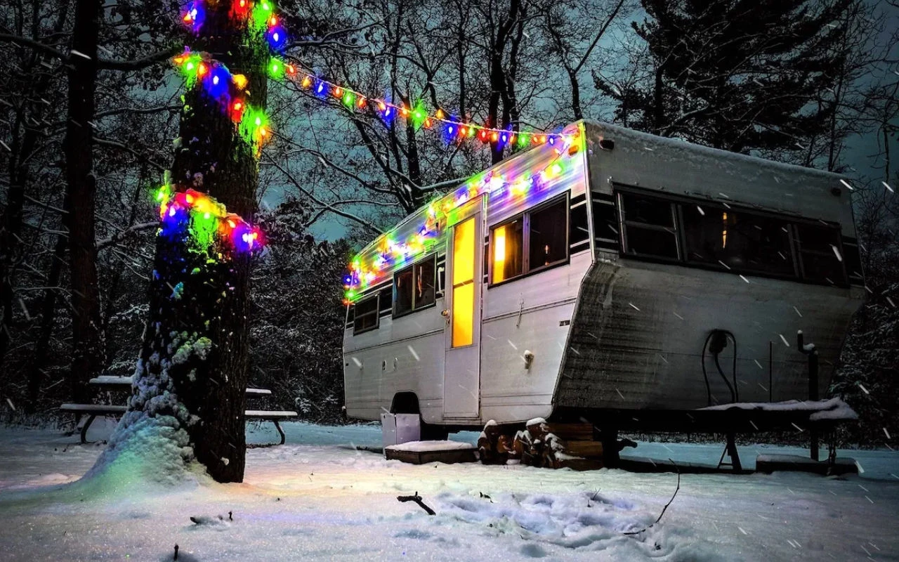 roulotte décorée de guirelandes colorées lumineuses en forêt un soir d'hiver