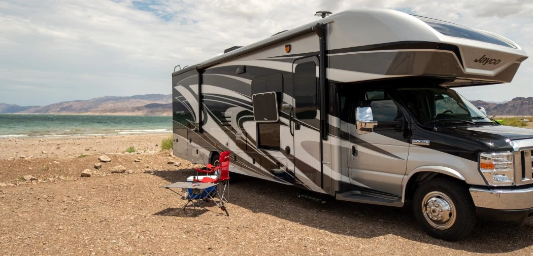 a Class C motorhome parked on a sandy seaside shore