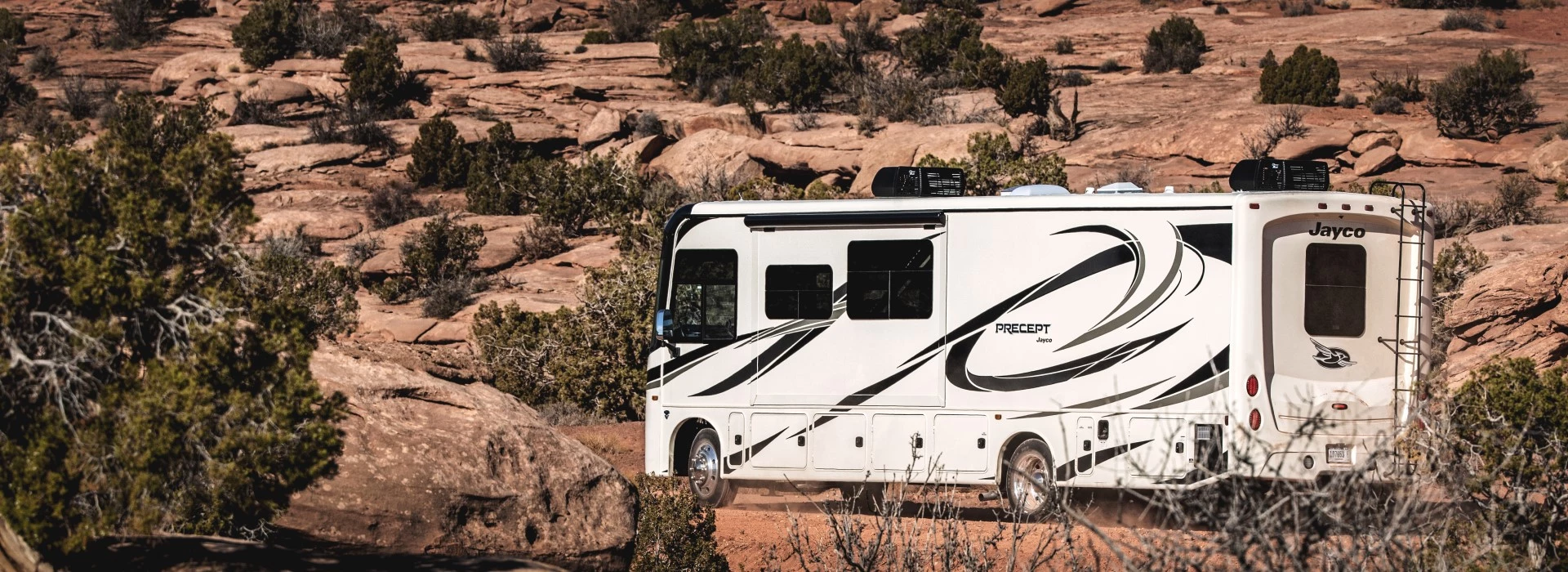 three quarter rear view of a Class A Jayco Precept motorhome parked in the desert