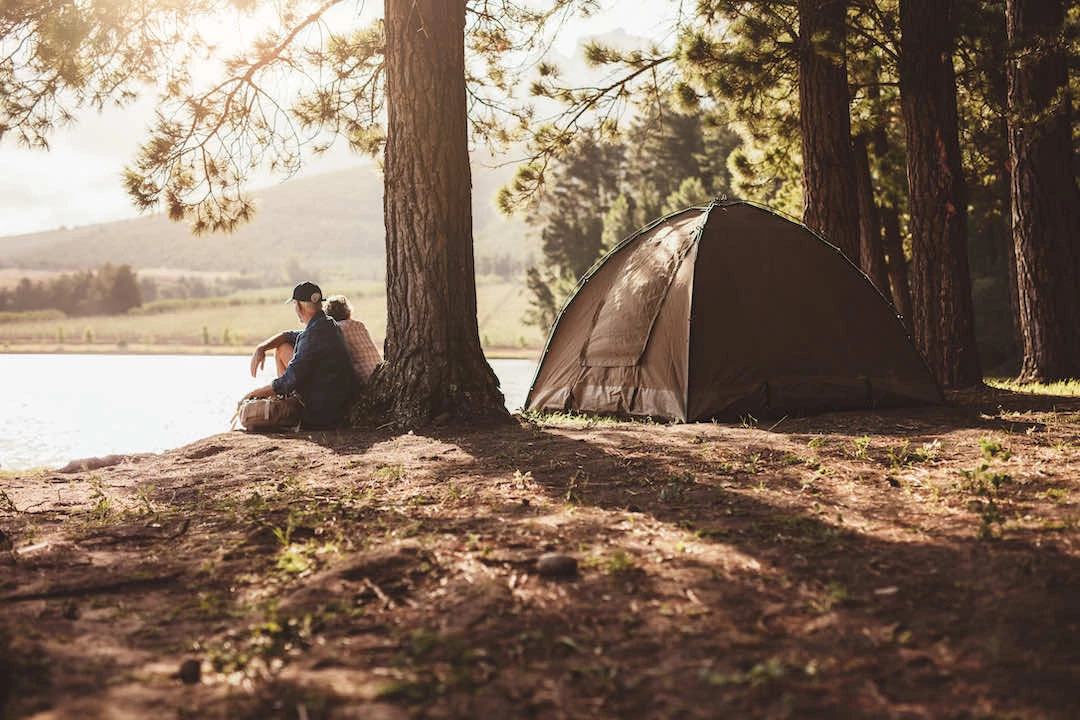 Un couple face à un lac campant en forêt.