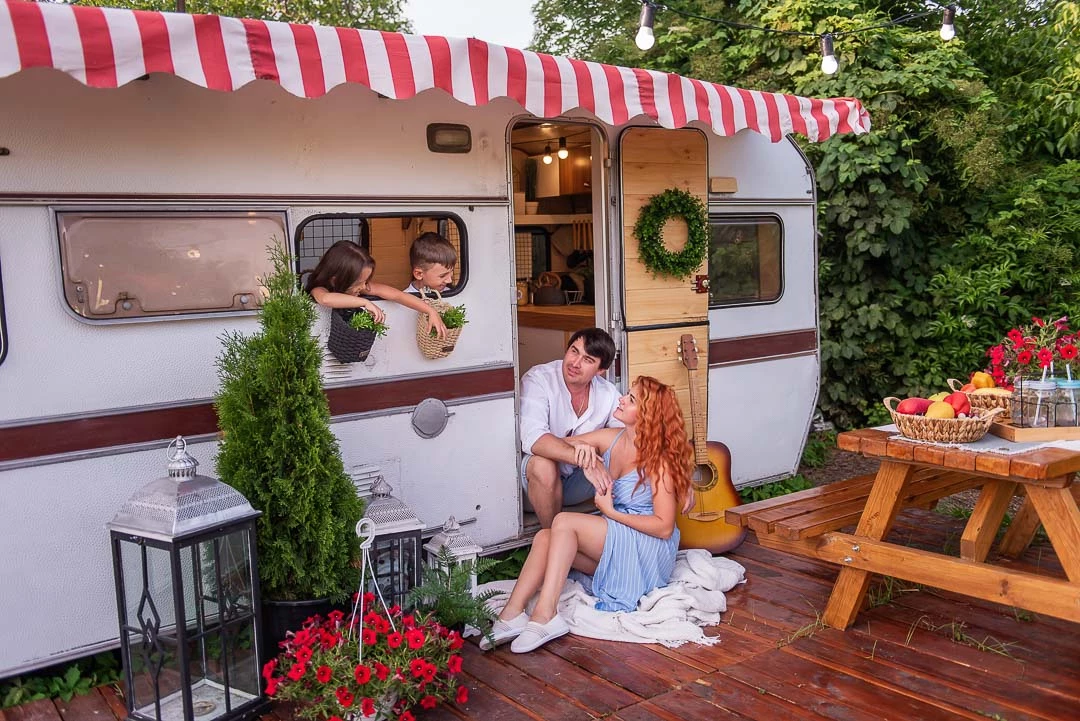 Famille assis dehors face à sa roulotte dans un camping