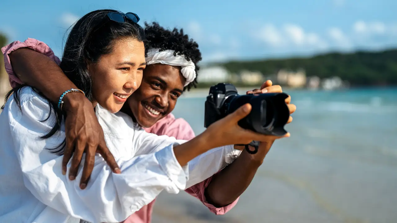 jeune couple en train de prendre des photos sur le bord de la mer