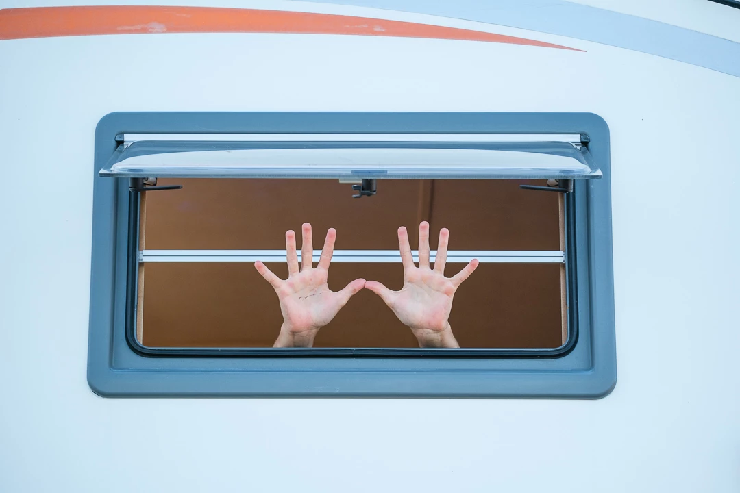 Main à travers une fenêtre de véhicule récréatif ouverte
