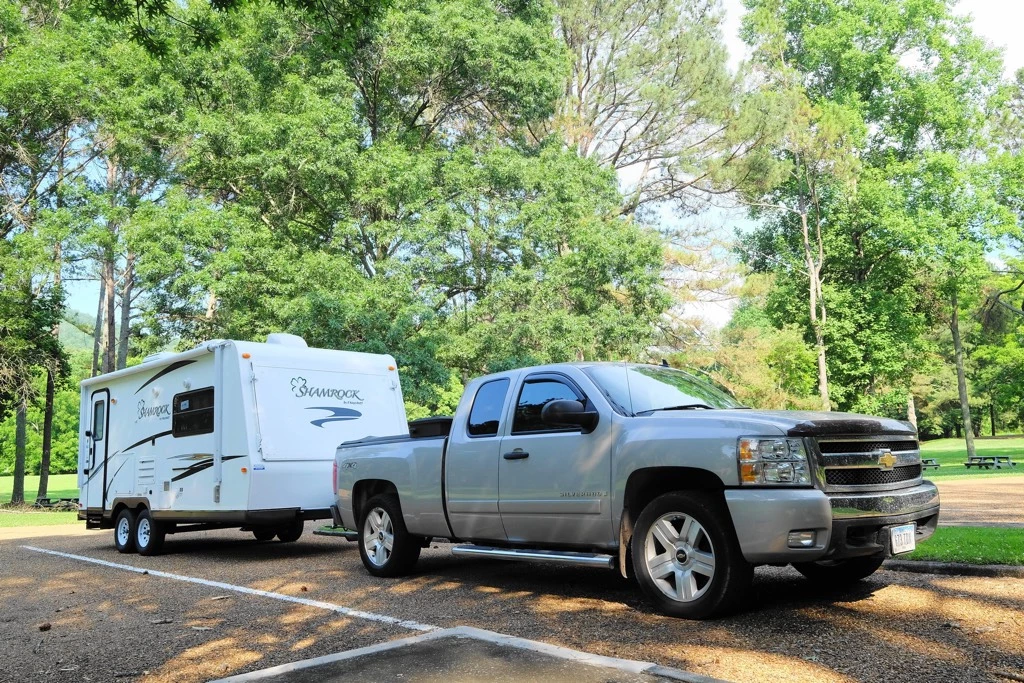  three quarter front view of a truck towing a Forest River Shamrock 2014 trailer