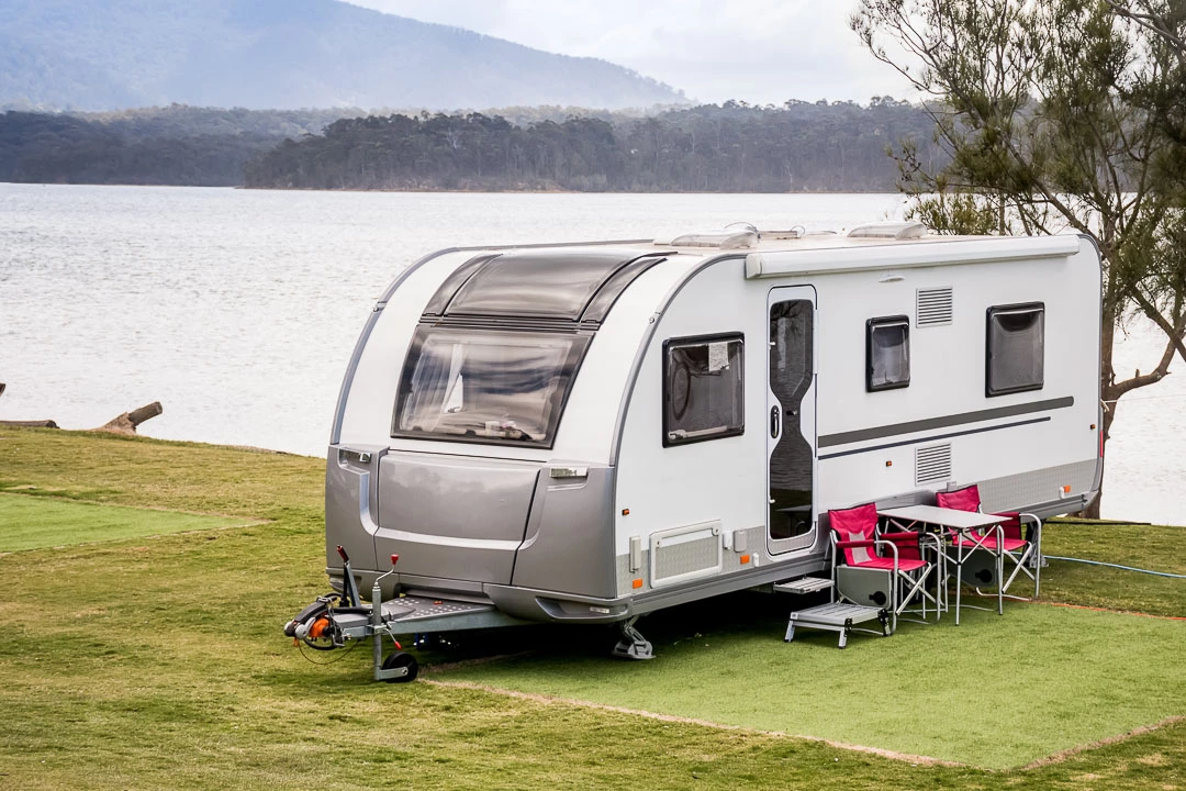 Roulotte stationnée sur un terrain de camping devant un étendu d'eau