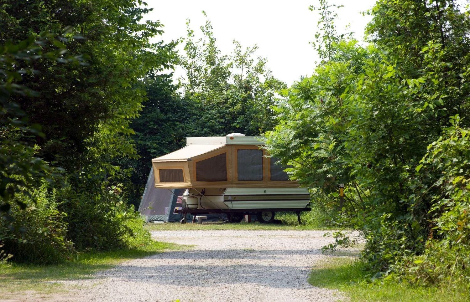 Vue éloignée d'une tente-roulotte installée sur un terrain en nature