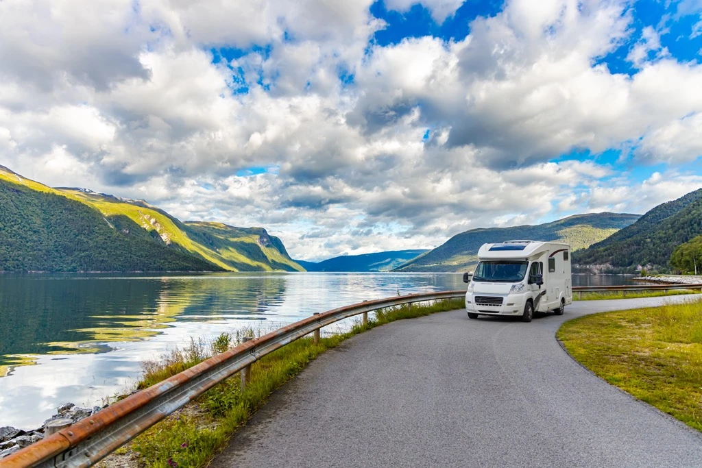 Un VR Motorisé roulant sur une petite route au bord d'un fleuve et des montagnes