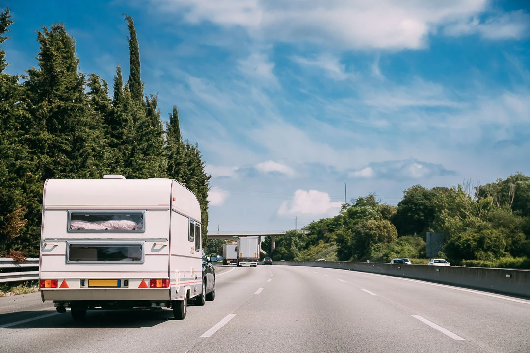 Voiture tractant une roulotte blanche sur l'autoroute