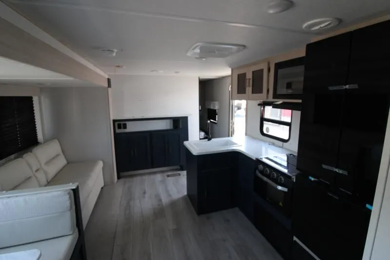 Vue de l’intérieur de l’Avenger 28QBSLE de Prime Time avec sofa, dinette familiale et cuisine en angle dans un style moderne épuré.