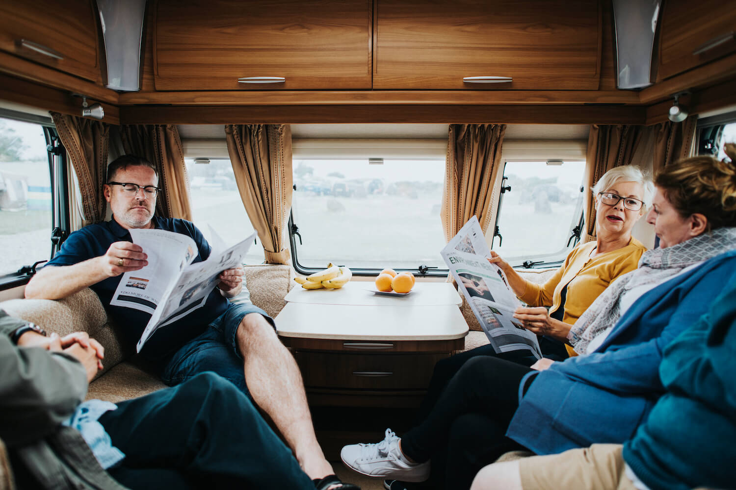 Une famille installée dans un campeur lisant le journal
