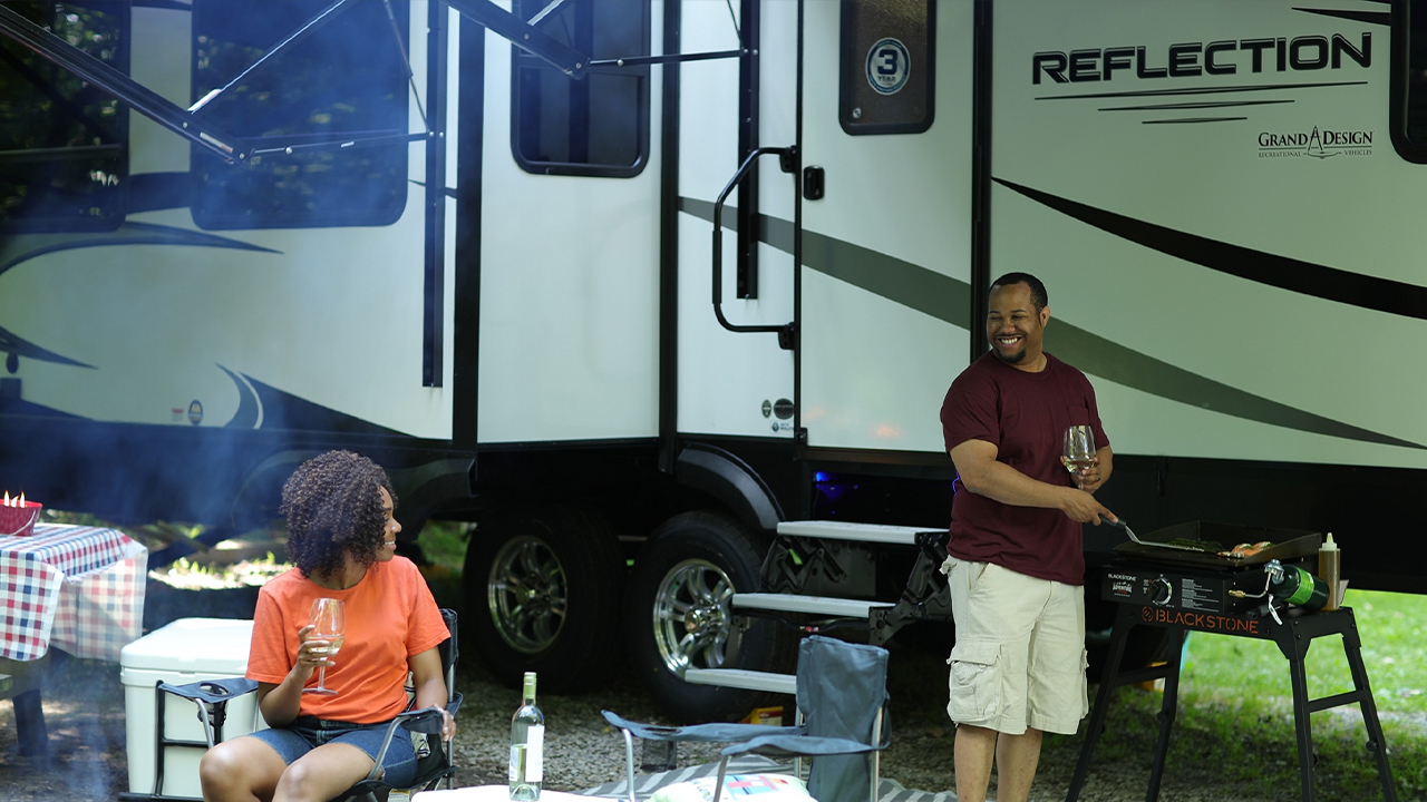 homme en train de faire de la cuisine pour sa copine près de sa roulotte