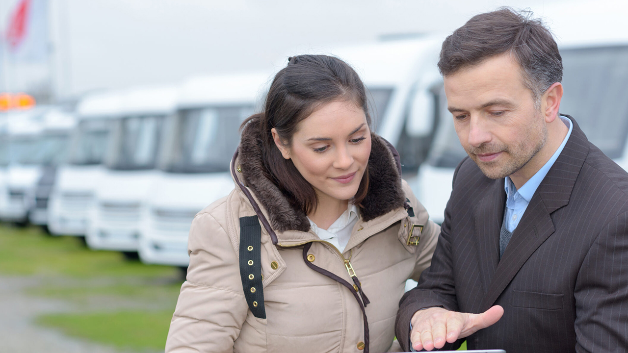 Vue d'un professionel montrant sur une tablette l'évaluation d'une roulotte à sa cliente