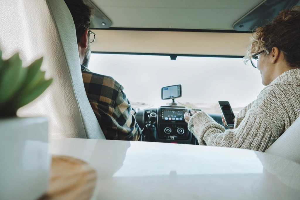 Couple à l’intérieur d’un VR consultant la carte sur un GPS, représentant les conseils de planification et d’organisation durant un road trip canadien.