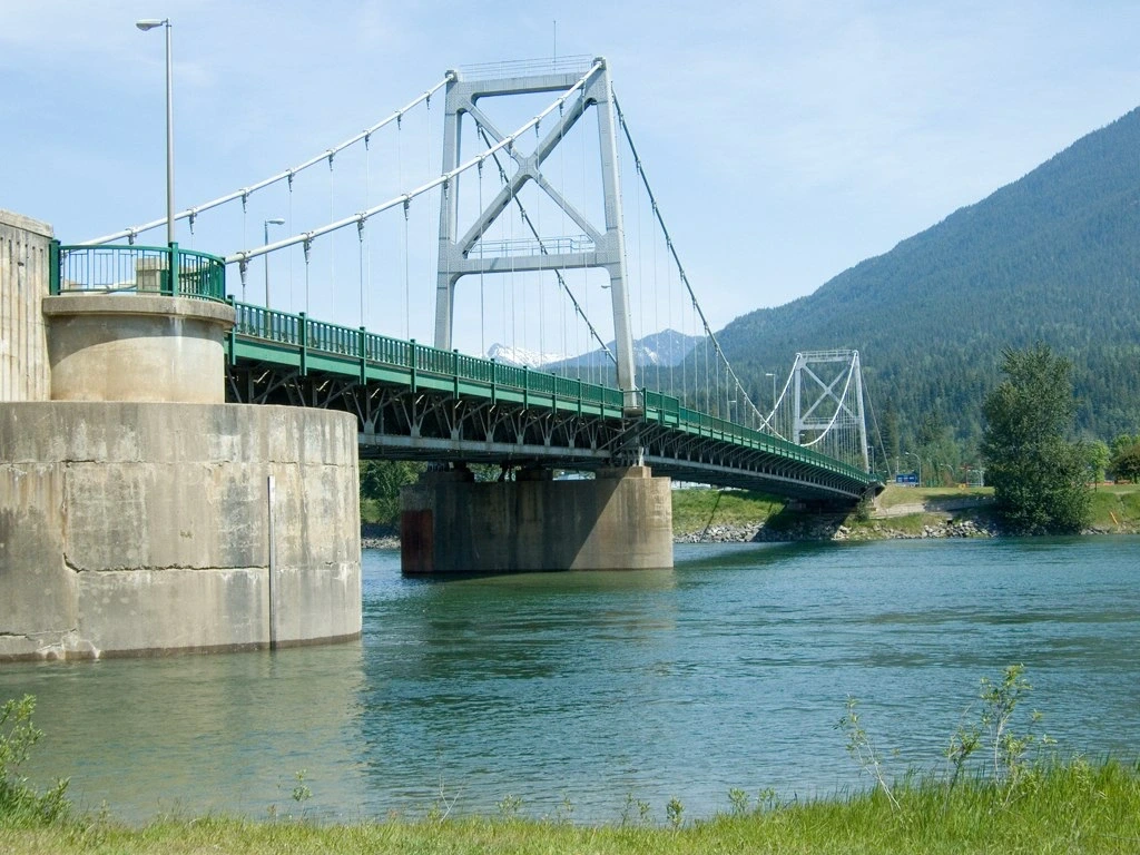 Pont suspendu de Revelstoke traversant une rivière entourée de montagnes, illustrant une étape pittoresque entre Revelstoke et Kelowna.