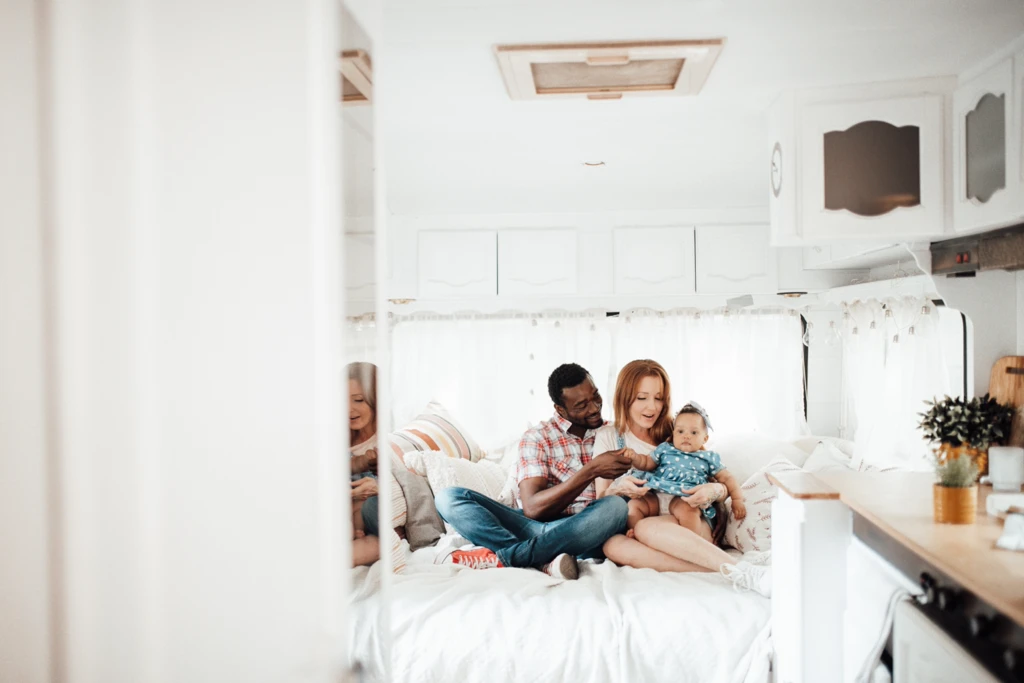Famille assise sur un lit à l’intérieur d’une roulotte lumineuse, illustrant l’importance du confort intérieur, de l’espace de vie et de la configuration des couchages.