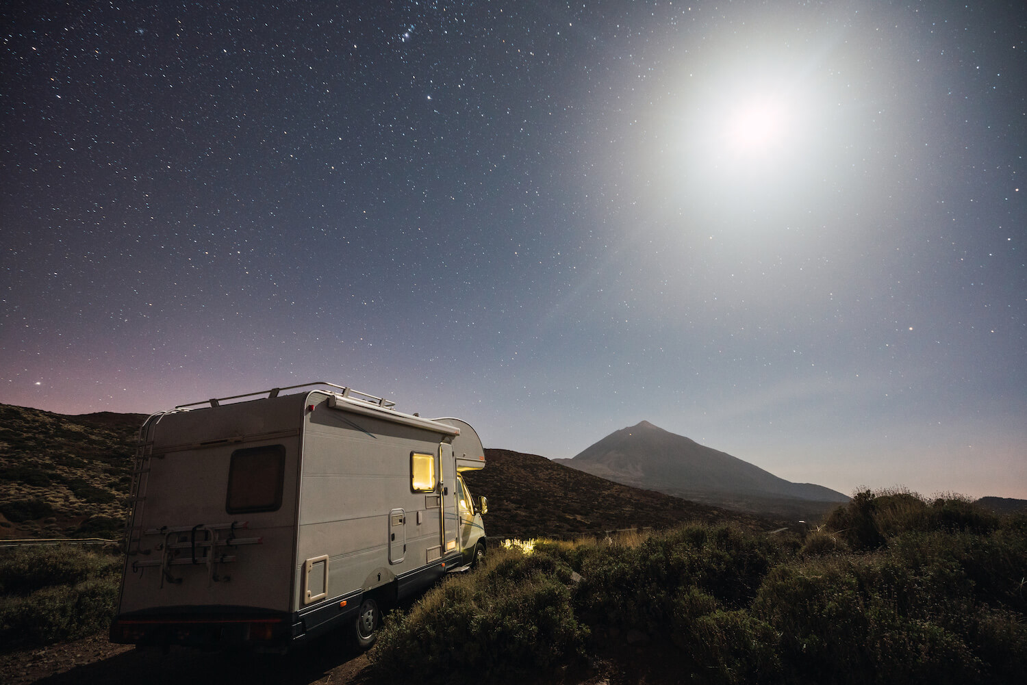 Vue 3/4 arrière d'un motorisé installé en nature sous les étoiles luminant le ciel