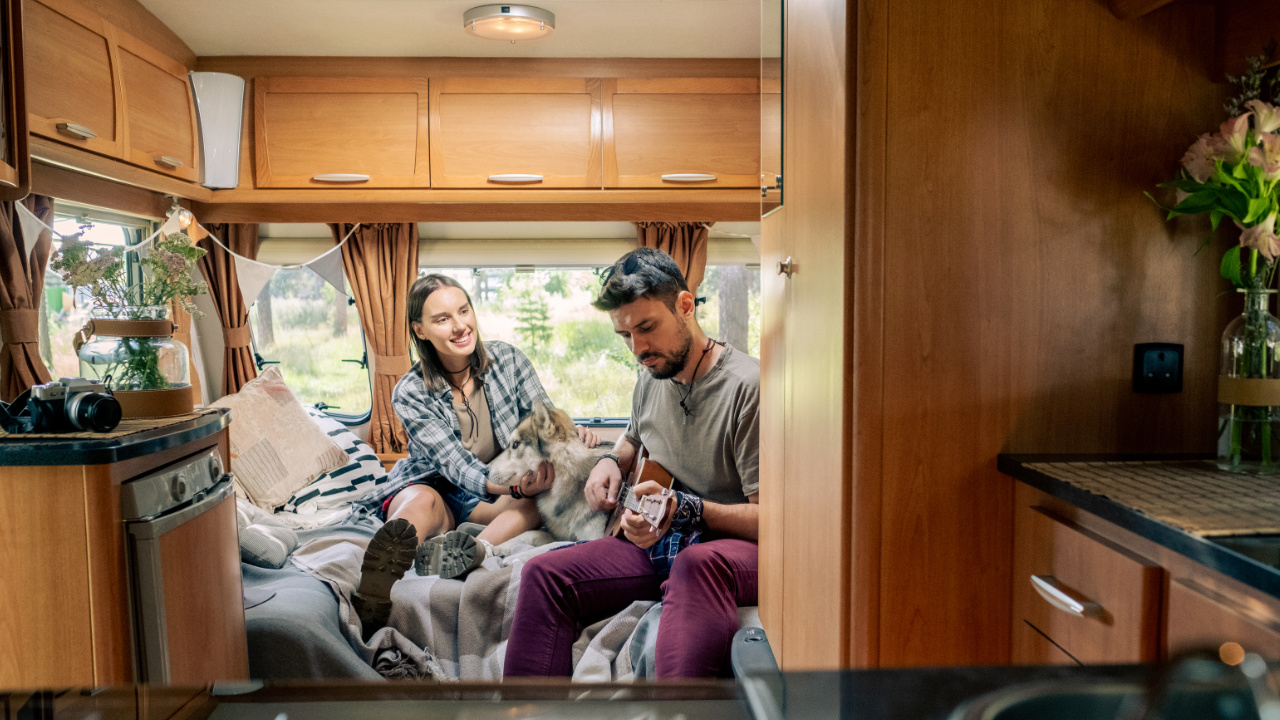 homme en train de jouer de la guitare pour sa copine dans une petite roulotte